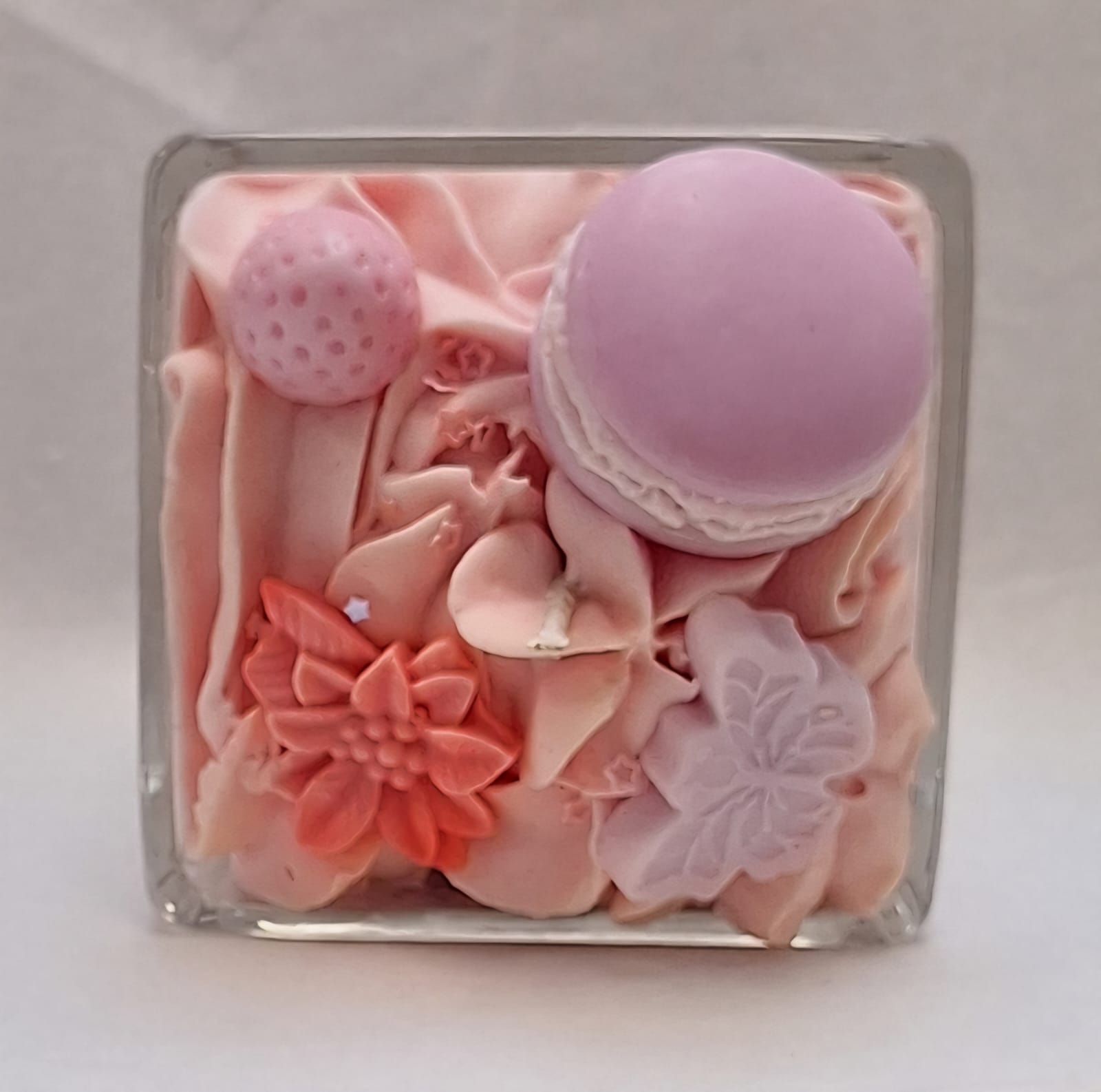 Handmade whipped wax dessert candle in glass jar with candy floss scent, topped with decorative sweets, macarons, and floral details.