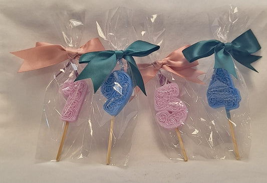 Handmade pink and blue number candles wrapped in clear gift bags with satin bows – scented decorative candles for baby showers and birthday parties.