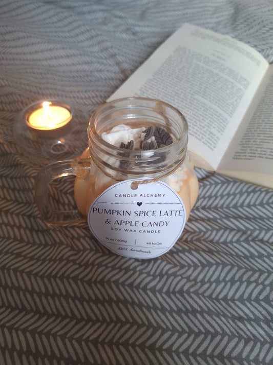 Pumpkin Spice Latte and Apple Candy soy candle in a mason jar with decorative toppings, next to a tealight and open book on a patterned blanket, perfect for autumn gifts and home décor.